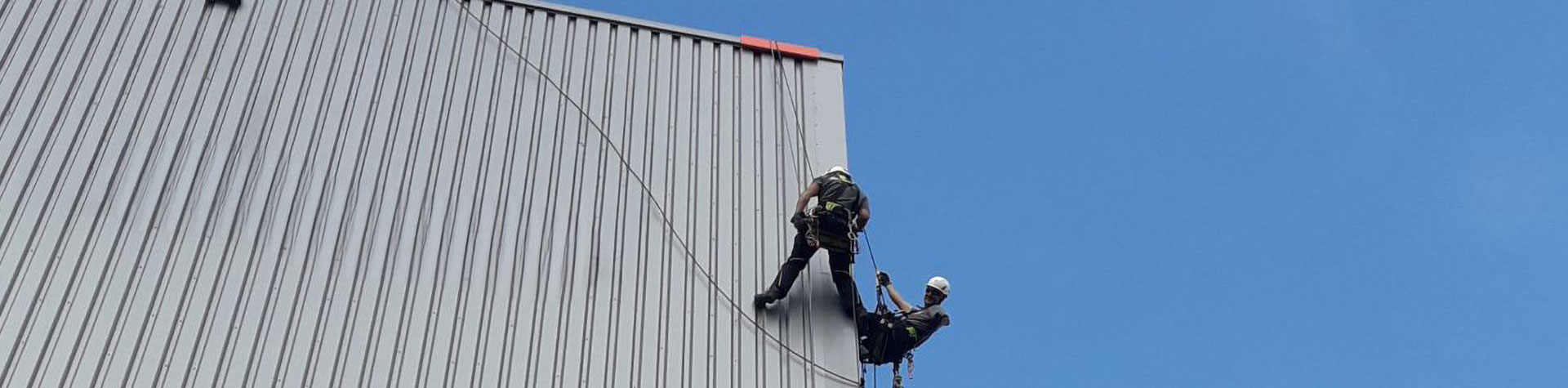 Zwei Arbeiter seilen sich von einem Dach ab.