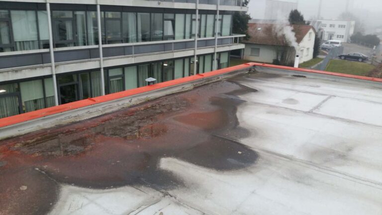 Flaches Dach mit Wasserpfützen und Bauschäden