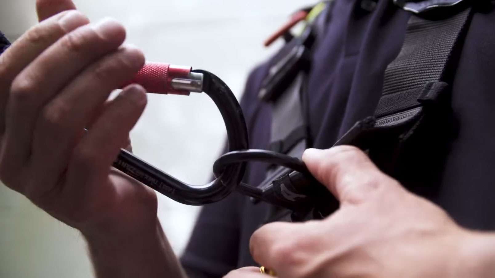 Person befestigt Karabinerhaken an Sicherheitsgurt